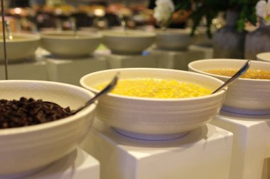 Tahta masada toplanmış, süt kavanozu ve ikonları gösteren yedi renkli tahıl kasesi sergileniyor. Düz yatak, kahvaltı, çeşni, kase, tahıl, mutfak, rahat. Yüksek kalite fotoğraf