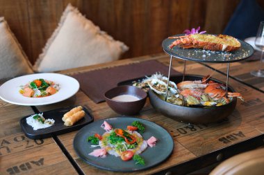 Istakoz, karides, limonlu ve limonlu midye tabağı. Taze salata, deniz ürünleri makarnası, ahşap masada kremalı sos. Zarif yemek deneyimi, gurme mutfağı..