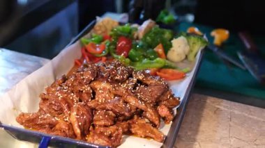 Açık büfe et tepsisi, solda bol soslu sulu sığır eti dilimleri ve sağda havuç ve mor karnabahar da dahil olmak üzere rengarenk sebze karışımı. 4k