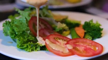 Şişeden zeytin yağı serpilmiş salata, bir kase taze Yunan salatası üzerine mayonez dökülmüş krema sosu.