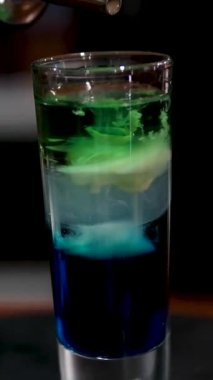 Barmenin likör ile katmanlı fondip yapmasına yakın çekim. Yüksek kalite 4k görüntü