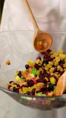 Sağlıklı karışım yavaş çekimde beyaz bir yüzeye düşüyor. Kuru üzümleri, kurutulmuş kayısıları ve kurutulmuş meyveleri karıştırın ve konyak pişirmek için ekleyin..