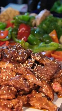 Açık büfe et tepsisi, solda bol soslu sulu sığır eti dilimleri ve sağda havuç ve mor karnabahar da dahil olmak üzere rengarenk sebze karışımı. 4k