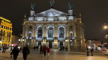 Opera Binası, insanlar etrafta dolaşıp huzurlu bir tatil ortamı yaratırken, akşam saatlerinde şenlikli dekorasyonlar ve sıcak ışıklarla hafifçe parlıyor. Lviv Ukrayna 12.10.2025