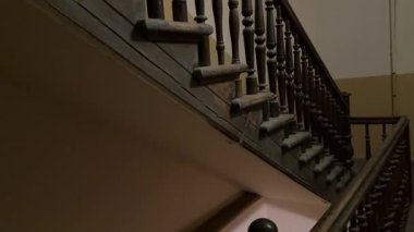 Büyük bir şehir binasının içindeki eski ahşap merdivenler gıcırdayan basamakları ve zengin yaşlı dokusu ile çarpıcı bir atmosferik iç mekan yaratarak eski kentsel apartmanlara doğru gidiyor..