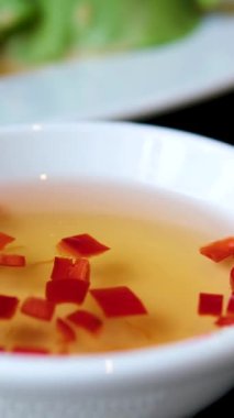 Kızarmış Vietnam usulü çıtır çıtır tavuk eti geleneksel balık sosu nuoc mama ile kırmızı biber dilimli küçük bir kasede otantik Asya sokak yemeği olarak servis ediliyor..