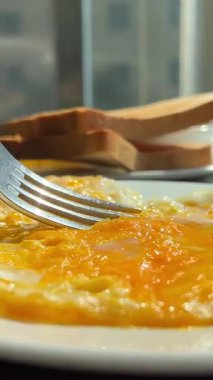 Yeşil tabakta kızarmış yumurta ve ekmek yemek. Yakın plan. Bakış açısı. Renkli arka plan. Tostlu geleneksel kahvaltı. Güneşli bir gün. Yüksek kalite 4k 