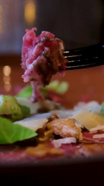 Restorandaki bir tabaktan çatalla Carpaccio parçalarını şişleyen kişiye yakın çekim. Yüksek kalite 4k görüntü