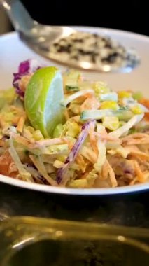 Evde salata karıştıran genç ve yakışıklı bir adam. Susam tohumları serpin.