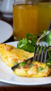 Tatlı biberli ve domatesli parlak sarı omlet çatal ve bıçakla kesilir. Salata yaprakları, çorba ve diğer Vietnam yemekleriyle servis edilen lezzetli bir öğle yemeği..