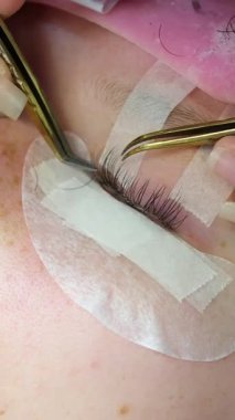 Kirpik uzatma süreci, deneyimli bir sanatçının şaşaalı bir görünüş için bireysel kirpiklerini hassasiyetle uygulamayı içeriyor. Profesyonel, hassas uygulama gelişmiş göz güzelliği. 4k