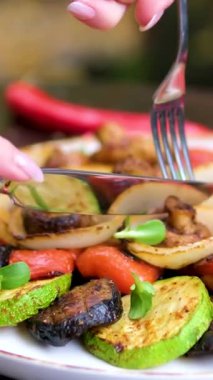 Bıçak ve çatal, tabağın yüzeyine konmuş ızgara sebze soğan biberi mantarlarını kesmek ve yemek için. Yüksek kalite 4k görüntü