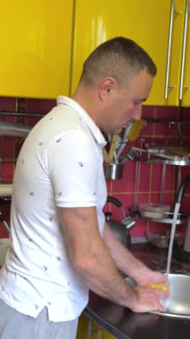 Adam bulaşık yıkıyor, elleri ve süngeri yakın tutuyor. Yüksek kalite 4k görüntü