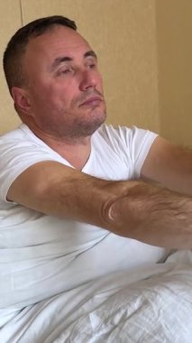 Genç ve yakışıklı bir adam yatakta uykusundan esneyerek ve mutlu uyanır. Adam harika bir uyku çekti. Uyku ve dinlenme için uygun koşullar. İyi sabahlar. Yeni bir günün başlangıcı.