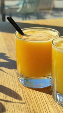 Güneşte portakal suyu. İki bardak. Pencerenin yanındaki ahşap masada bir zeytin dalı bir restoranda şehre bakıyor.