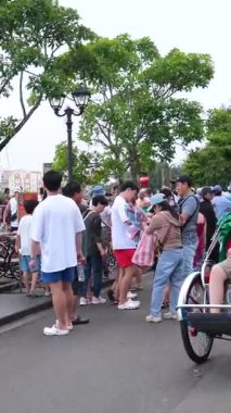 Hoi 'nin Riverside Mahallesi. Japon köprü arabaları ile Vietnam. Sokaklarda turistler geziyor, yerel kafeleri keşfediyor ve otantik kültürel yaşam tarzının tadını çıkarıyor.