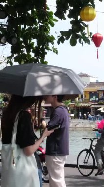 Hoi 'nin Riverside Mahallesi. Japon köprü arabaları ile Vietnam. Sokaklarda turistler geziyor, yerel kafeleri keşfediyor ve otantik kültürel yaşam tarzının tadını çıkarıyor.