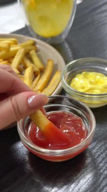 Koyu beton arka planda tuz ve baharatlı çıtır patates kızartması. Citrus çayı, bir tabak patates kızartması, ketçap, hardal ve peynir sosu..