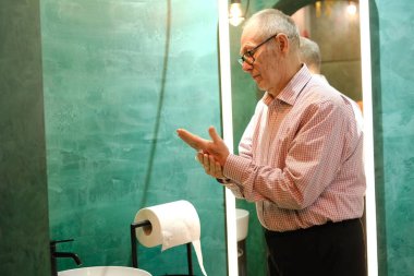 Yaşlı adam banyo lavabosunda akan suyun altında ellerini yıkıyor. Ev, apartman dairesi lüks bir yaşam tarzı. Yüksek kalite fotoğraf