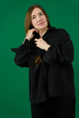 Kendine güvenen genç iş kadını saçını düzeltiyor, beyaz bir arka plana karşı mavi bir takım elbise içinde profesyonellik ve tarz yayıyor. Yüksek kalite fotoğraf