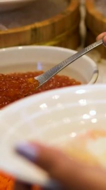 Deniz ürünleri büfesinde kırmızı havyarı kaşıkla kepçelemek. Yüksek kalite 4k görüntü