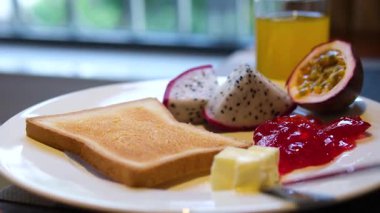 Taze meyveli kahvaltı tepsisi, bir dilim ekmek, bir bardak portakal suyu ve yoğurt, ahşap tepside sıralanmış, sağlıklı ve besleyici yemek ortamı yaratıyor. Sağlıklı beslenme ve yaşam tarzı. Yüksek kalite