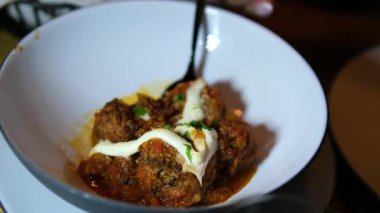 Sobadaki paslanmaz çelik bir tencerede kremalı sosta kaynamış köftelerin yukarıdan görünüşü. Yüksek kalite 4k görüntü