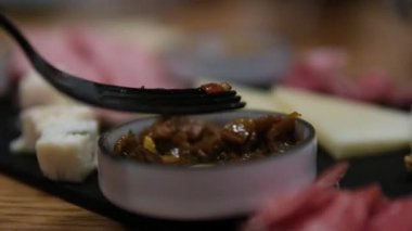 Etleri Charcuterie tahtasından çatalla alıp çeşitli pişirilmiş et ve sosislerle kapatıyoruz. Yüksek kalite 4k görüntü