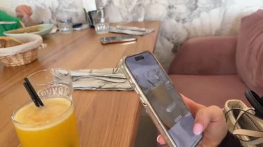 Bir kız portakal suyu içen kadının fotoğrafını çekiyor. Cep telefonundan enfes fotoğraflar çekiyor. Yüksek kalite 4k görüntü