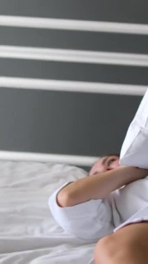 Kafkasyalı tembel yetişkin kadın, sabah yatak odasında uyanıyor gülümsüyor rahat, yumuşak bir yatak örtüsü içinde uzanıyor uykulu bir kadın, uykudan sonra rahatlıyor neşeli bir hafta sonu istirahatinin keyfini çıkarıyor..