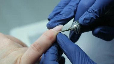 Tırnak törpüleme ustası, adım adım jöle sürüyor. Manikürcü, tırnak törpüsü kullanıyor. Önce tırnak derisini matkapla, sonra çubukla sök..