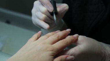 Tırnak törpüleme ustası, adım adım jöle sürüyor. Manikürcü, tırnak törpüsü kullanıyor. Önce tırnak derisini matkapla, sonra çubukla sök..