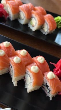 Sushi siyah tabakta yuvarlanıyor, karanlık arka planda, yakın plan. Japon mutfağı. Yüksek kalite 4k görüntü
