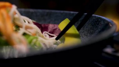 Buharda pişen sıcak pedli Tayland Wok karidesi sebzeli tavuk biberli yumurta eriştesi ve tahta çubuklar. Avokado Asya çubuklarıyla erişte tutan vermicelli.