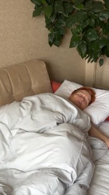 Huzur, yorgunluk ve stres rahatlığı içinde yatağında uyuyan ve okşayan yaşlı bir emekli kadın. Uyumak, rüya görmek ve yatak odasında köpekle kırıştırmak, rahatlamak ya da sarılarak kestirmek.