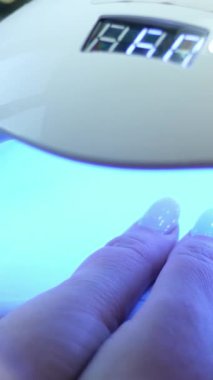 Jel manikür için UV LED lambanın altında bir elin iyileştiğini gösteren kısa bir video. Yüksek kalite 4k görüntü