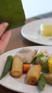 Beyaz bir tabakta kızarmış börek, mısır, domates, yeşil sebze, Asya yemekleri, Asya yemekleri, kahvaltıda yenir. Palmiye yaprağında pirinç keki