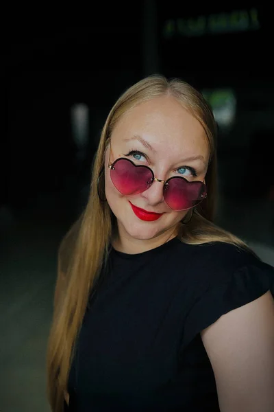 Pembe gözlüklü bir kızın portresi yukarı bakıyor.