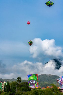 Mavi gökyüzü ile balon festivali ve arkada Tusa tepesi - Venedik, Antioquia, Kolombiya.