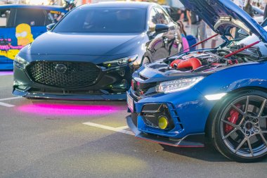 Gece sokak sahnesi İki modifiye edilmiş spor araba, siyah Nissan GT-R mavi kaput, mor LED ışıklar ve kırmızı spor araba sarı detay, turbo motorlu, pa Kyiv, Ukrayna - 21 Eylül 2025