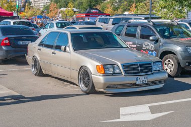 Çapraz park halindeki dört kapılı özel yapım siyah jantları olan ve halka açık otoparkta süspansiyonunu indiren diğer araçlar Kyiv, Ukrayna - 21 Eylül 2025