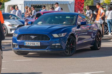 Caddeye park etmiş çarpıcı mavi bir Ford Mustang 'in yer aldığı bir araba fuarı ya da sergisi sokak manzarası Kyiv, Ukrayna Çevre Bölgesi - 21 Eylül 2025