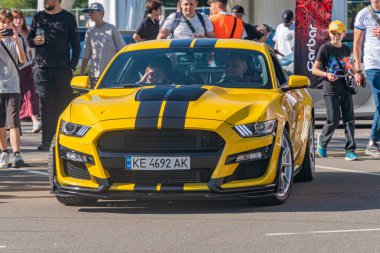 Sade Sarı Ford Mustang kaslı araba, siyah yarış çizgileri olan bir açıyla sergileniyor, açık hava etkinliğinde yer alan Kyiv, Ukrayna - 21 Eylül 2025