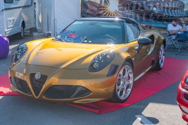 Sarı Alfa Romeo spor arabası araba fuarında kırmızı halıda, parlak tasarım, açık kokpit, parlak yüzey yansıtan ışık, kırmızı halı, Ukrayna 'nın Kyiv kentindeki diğer araçlar - 21 Eylül 2025