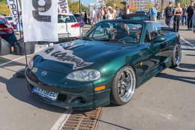 Koyu yeşil renkli, muhtemelen 60 'lardan ya da 70' lerden kalma beyaz çizgili bir spor arabanın yakın plan görüntüsü, asılı duran bir araba fuarında çekildi. Doğal gün ışığı Oth Kyiv, Ukrayna - 21 Eylül 2025