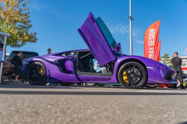 Canlı mor Lamborghini, şehir caddesinde gündüz vakti park edilmiş eşsiz üstü açılabilir kapıları, arka planda etkinlik ya da toplanma, potansiyel halka açık sergi ya da adil Kyiv, Ukrayna - 21 Eylül 2025