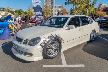 Bir araba fuarında modifiye edilmiş açık renkli bir sedanın yakın görüntüsü, özel tekerlekler, yan etek uzantıları ve kaput kaplama gününde havalandırmalar Kyiv, Ukrayna - 21 Eylül 2025