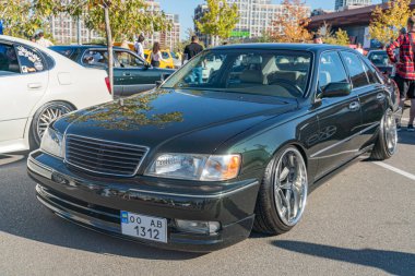 Siyah dört kapılı Lexus sedan, renkli camlar ve alaşımlı tekerlekler beyaz plaka K 132 'yi gösteriyor. Diğer arabalar da park halinde. Kyiv, Ukrayna - 21 Eylül 2025