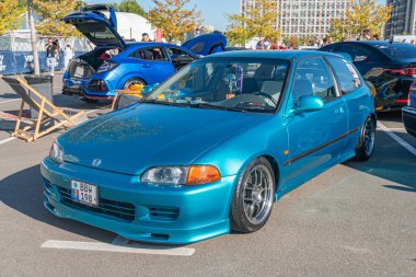 Bir otomobil fuarında mavi Honda Integra R tipi araba, stratejik olarak görüş için yerleştirilmiş, siyah jantlar, canlı ayar, bulanık arka plan araçları, Kyiv, Ukrayna - 21 Eylül 2025