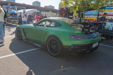 Pürüzsüz tasarım ve parlak yansımalarla dolu yeşil bir spor arabanın olduğu canlı bir açık hava sahnesi sağ arka plan el Kyiv, Ukrayna - 21 Eylül 2025